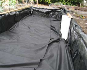 Photo of a wicking bed with weed matting layed out in it.