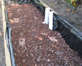 Photo of stones layed out in the bottom of a wicking bed.